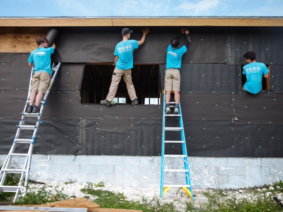 Abaco, The Bahamas :: Crewmembers help to wrap a house to make it weather-proof after a hurricane destroyed homes in the Abaco Islands.